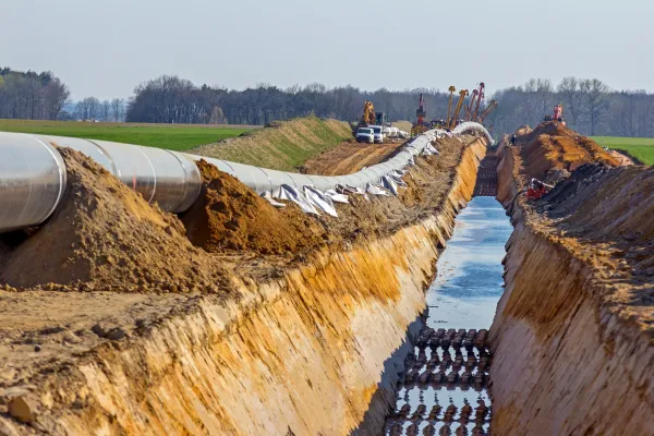 Man sieht auf eine Baustelle mit viel aufgerissener Erde, einer großen Vertiefung für bereitliegende Rohre und Baufahrzeuge